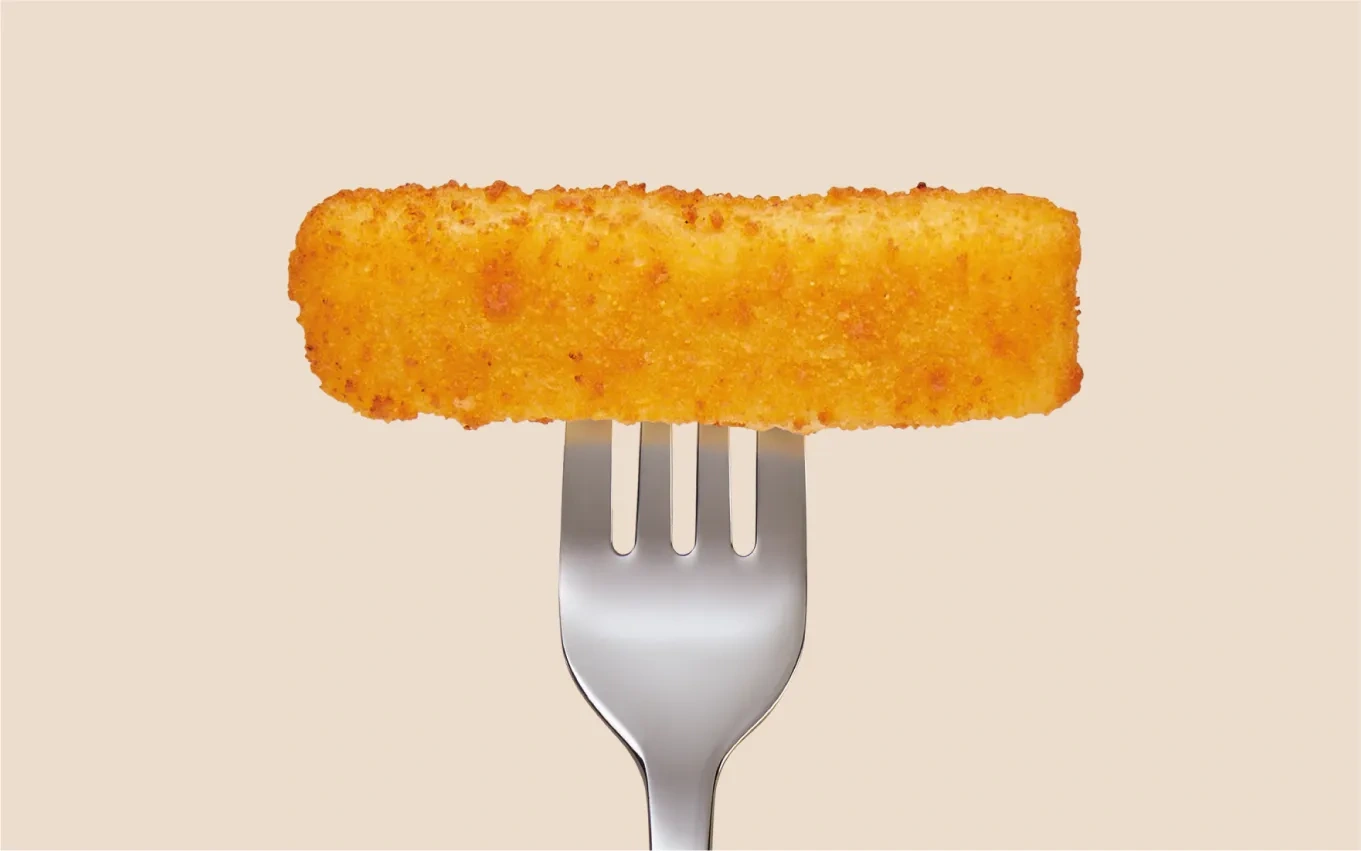 Photography of a singular, golden fish finger on a fork.